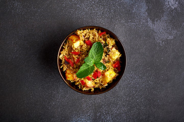 vegetarian paneer biryani at black background. paneer biryani is traditional veg indian cuisine dish with paneer cheese, basmati rice, masala, chili pepper, mint and many another spices. Copy space