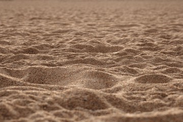 The sand on the beach in the rays of the warm sunset sun hills cast cool shadows.