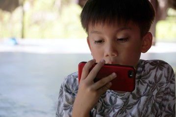 Asian black short hair boy is watching a movie in a red mobile phone.