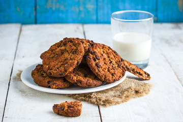 chocolate cookies on plate glass of milk on white rustic wooden table blue background 