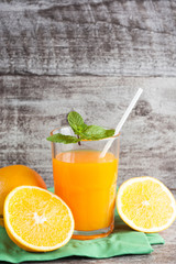 Close-up of a glass of orange juice with oranges fruits on wooden and stone background. Vitamins and minerals. Healthy drink and beverage concept.