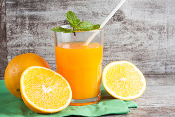 Close-up of a glass of orange juice with oranges fruits on wooden and stone background. Vitamins and minerals. Healthy drink and beverage concept.
