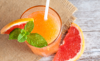 A glass of ripe grapefruit with juice on wooden table close-up