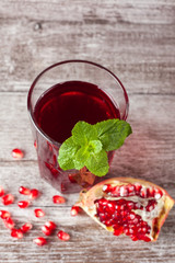 A glass of pomegranate juice with fresh pomegranate fruits on wooden table. Vitamins and minerals. Healthy drink concept.