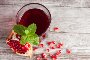 A glass of pomegranate juice with fresh pomegranate fruits on wooden table. Vitamins and minerals. Healthy drink concept.