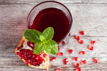 A glass of pomegranate juice with fresh pomegranate fruits on wooden table. Vitamins and minerals. Healthy drink concept.