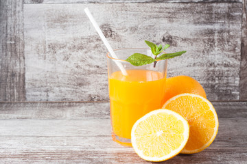 Close-up of a glass of orange juice with oranges fruits on wooden and stone background. Vitamins and minerals. Healthy drink and beverage concept.