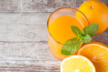 Close-up of a glass of orange juice with oranges fruits on wooden and stone background. Vitamins and minerals. Healthy drink and beverage concept.