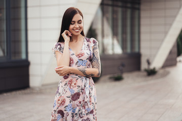 Attractive brunette girl in colored dress posing near modern building