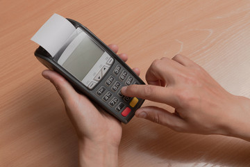 A person holds in his hand a terminal for paying for purchases in a store using bank cards or NFC