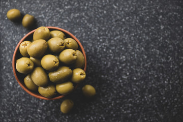 Green olives in a bowl on a dark background