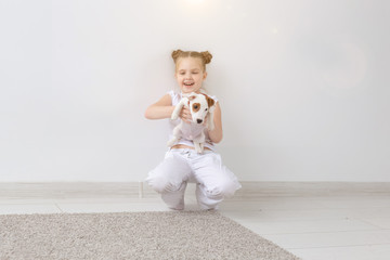 Fototapeta na wymiar Dogs, pets and animal concept - Little child girl sitting with puppy Jack Russell Terrier