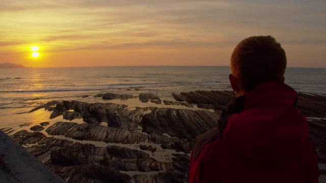 Slow zoom in woman contemplates sunset