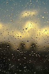 Ventana con gotas de agua y fondo difuminado de un paisaje.
