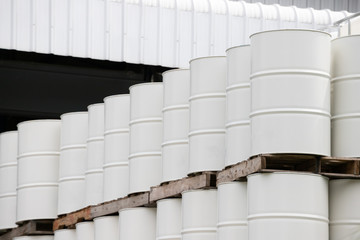 white oil barrels stack on industry pallet  at factory stock yard. white steel drum container. metal tank of liquid chemical. size 200 litres.