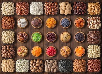 assorted nuts and dried fruits on wooden table, top view. healthy snack in bowls, food background.