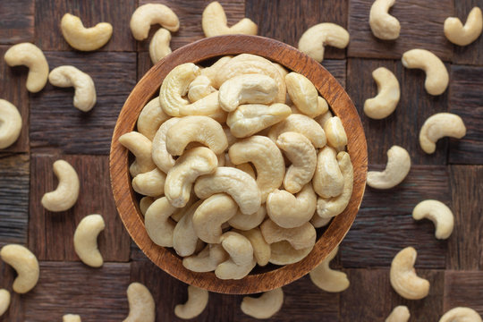 cashew nuts peeled raw in wooden bowl, top view.