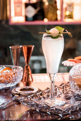 Beautiful white cocktail in elegant high glass on a crystal plate on the table in a restaurant on the background of the interior. Close-up. Space