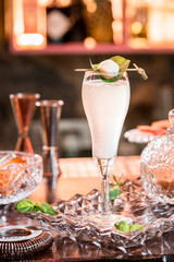 Beautiful white cocktail in elegant high glass on a crystal plate on the table in a restaurant on the background of the interior. Close-up. Space