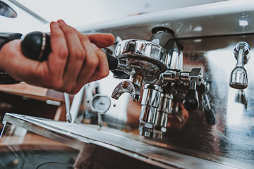 Close up of hand putting filter holder into coffee outlet