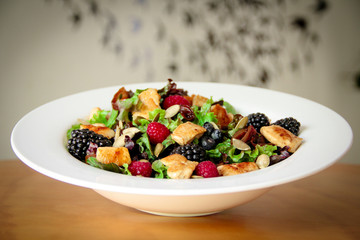 Healthy salad bowl with grilled chicken, caramelized onion and berries.