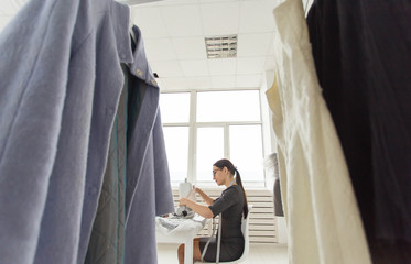 Tailor, people and seamstress concept - Low angle view of attractive young woman fashion designer working in studio