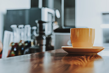 Close up of orange cup standing on the wooden surface