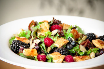 Healthy salad bowl with grilled chicken, caramelized onion and berries.