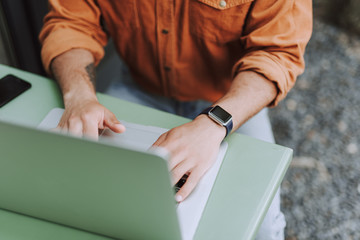 Young man in orange shirt using modern notebook
