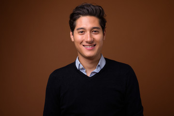 Young multi-ethnic handsome man against brown background