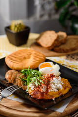 Delicious breakfast with boiled eggs, pumpkin puree, lettuce, cheese and fresh bread on a black plate on a yellow set on a wooden table in a restaurant. Close up. Space