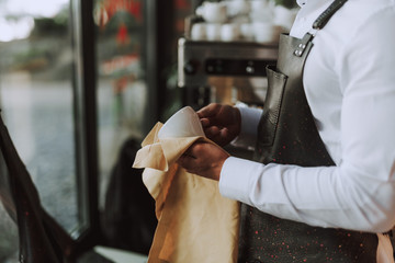 Professional bartender wiping white cup with cleaning cloth