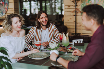 Three cheerful friends chatting and laughing in cafe