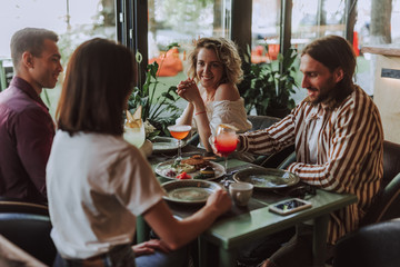 Cheerful friends spending time in cozy cafe