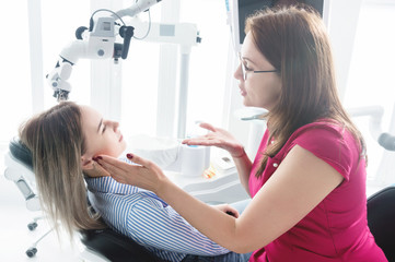 Dentist woman doctor talking to a young patient sitting on the dentist chair in a medical office. The first conversation with the client and external visual inspection