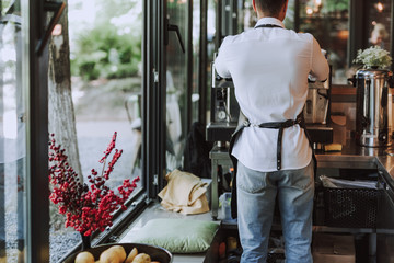 Barman in white shirt using professional coffee machine