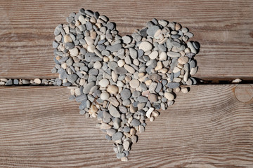 heart of sea pebbles on wood texture