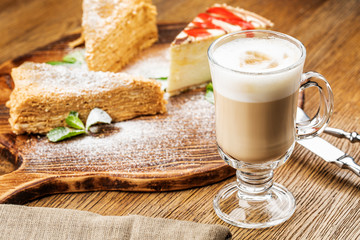 Cappuccino Cup with latte on wooden background. Beautiful foam, green ceramic Cup.
