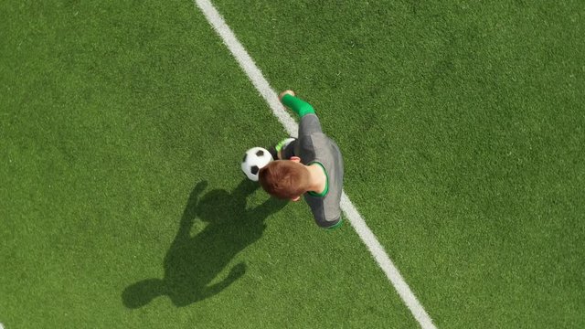 Top view from drone on football field football player stuffs ball. Soccer trains before match on football field on sunny day.
