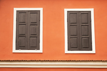 Naklejka premium vintage windows with wooden shutters closed and orange wall