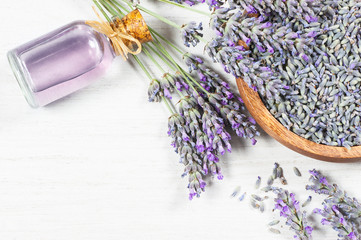 Glass bottle of Lavender essential oil with fresh lavender flowers and dried lavender seeds on white rustic table, aromatherapy spa massage concept. Lavendula oleum