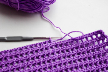 Ball of yarn, crochet hook and a piece of knitted linen