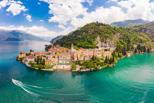 Beautifull aerial panoramic view from the drone to the Varenna - famous old Italy town on bank of Como lake. High top view to Water landscape with green hills, mountains and city in sunny summer day.
