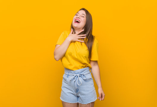 Young Woman Teenager Wearing A Yellow Shirt Laughs Out Loudly Keeping Hand On Chest.