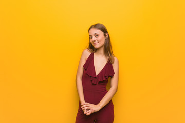 Obraz premium Young natural woman wearing a red dress against an orange wall