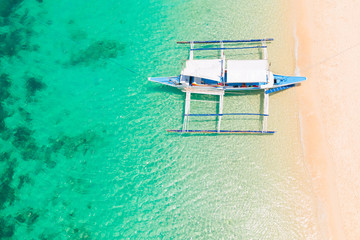 Traditional Philippine boat in the tropical lagoon. White sandy beach.