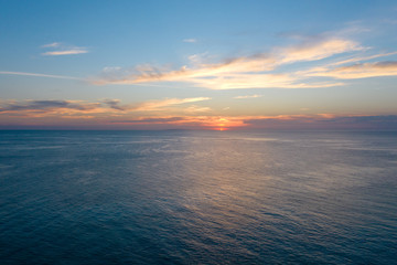 Sunset over the sea in calm weather. Calm sea in the evening. The sun on the horizon.