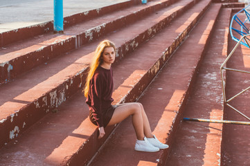 Young blonde girl in skirt sitting on painted stairs