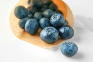 Paper cone with fresh blueberry on light background