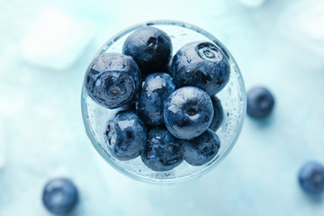 Glass with fresh blueberry on color background, closeup